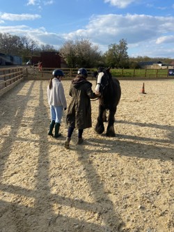 Two females with a black pony with a white face in an outdoor arena