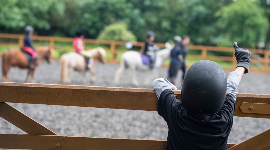 child watching riding lesson